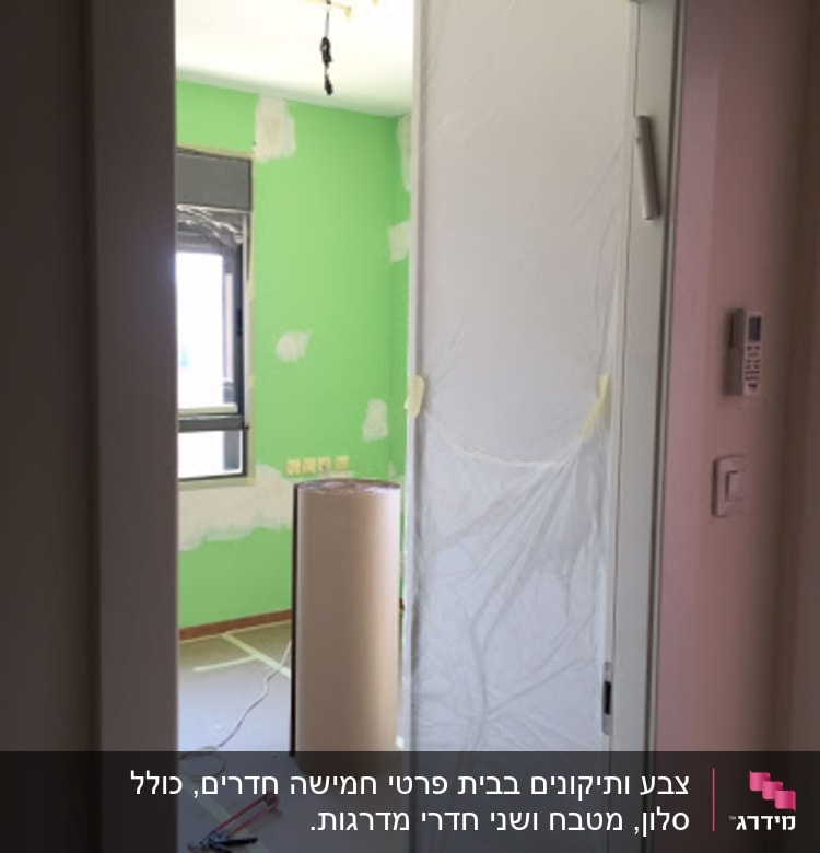 חדר עם קיר ירוק, גליל נייר, כלי צביעה על הרצפה